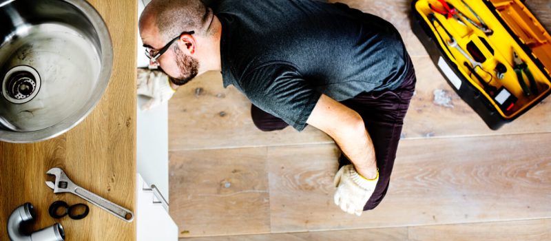 Man fixing kitchen sink - image by © rawpixel